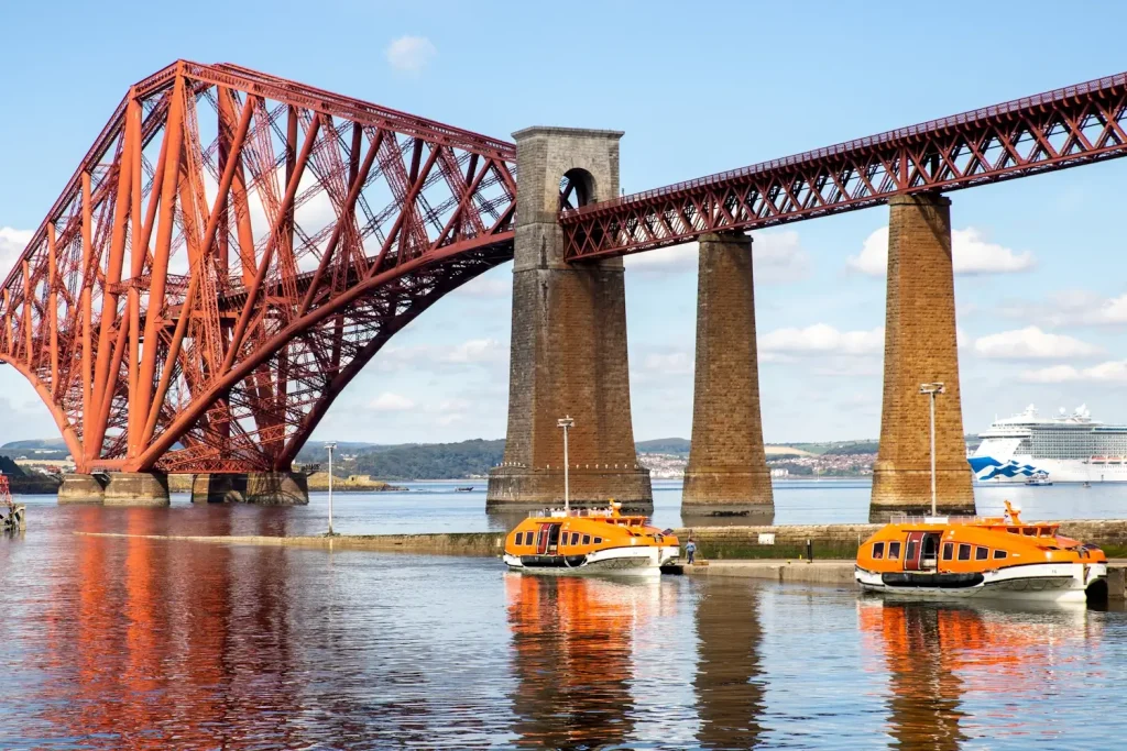 tender boats at the hawes pier with a MSC cruise ship anchored behind the forth bridge