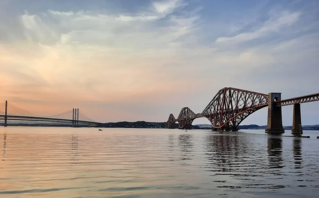 forth bridges in south queensferry at sunset over the still waters of the firth of forth