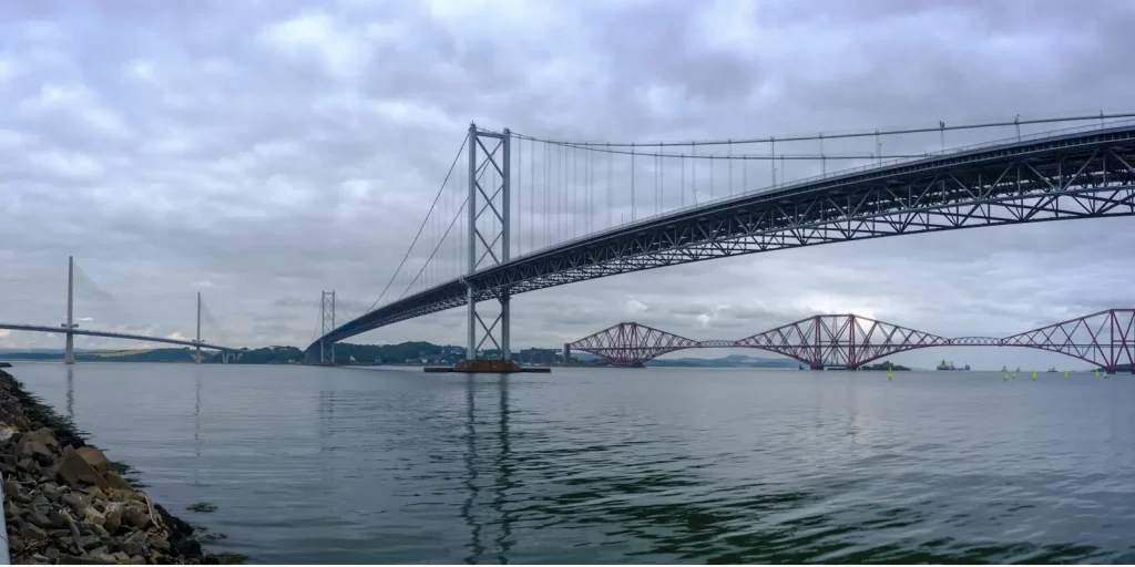 A panoramic view of the three Forth bridges crossing the Firth of Forth at Queensferry on a cloudy day.