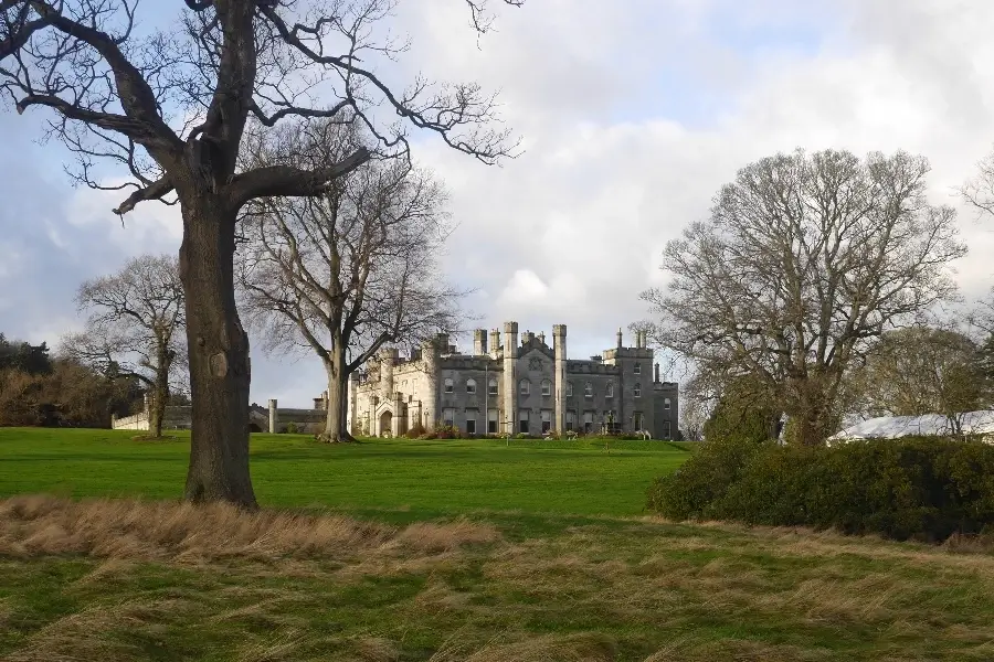 Dundas Castle seen from a distance across its estate lawns, framed by large trees on the Dundas Estate a place to visit near South Queensferry.