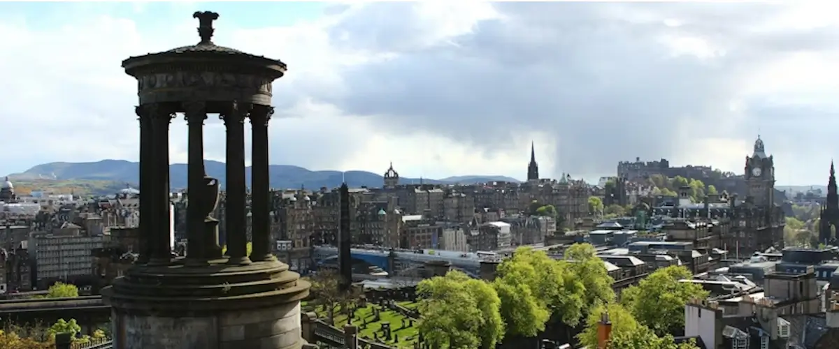 Panoramic view from Calton Hill over Edinburgh city centre, with the Dugald Stewart Monument in the foreground and surrounding Edinburgh free green spaces visible below