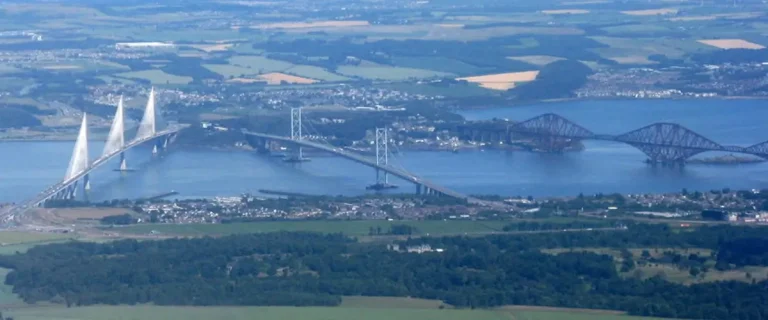 Ariel view of places to visit near queensferry showing the three Forth bridges crossing the Firth of Forth near South Queensferry, including the Queensferry Crossing, Forth Road Bridge and Forth Bridge.
