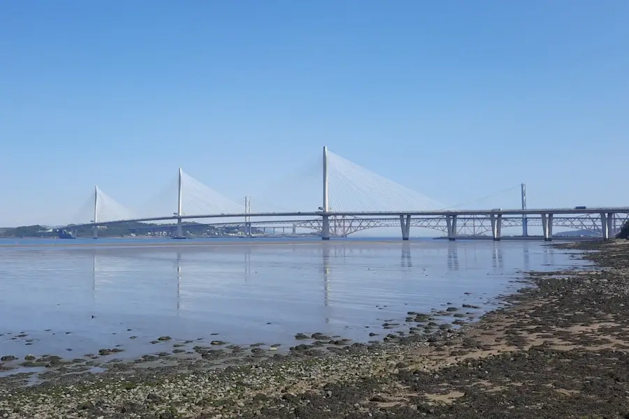 The completed Queensferry Crossing spanning the Firth of Forth at low tide, with exposed shoreline and fixed bridge alignments visible