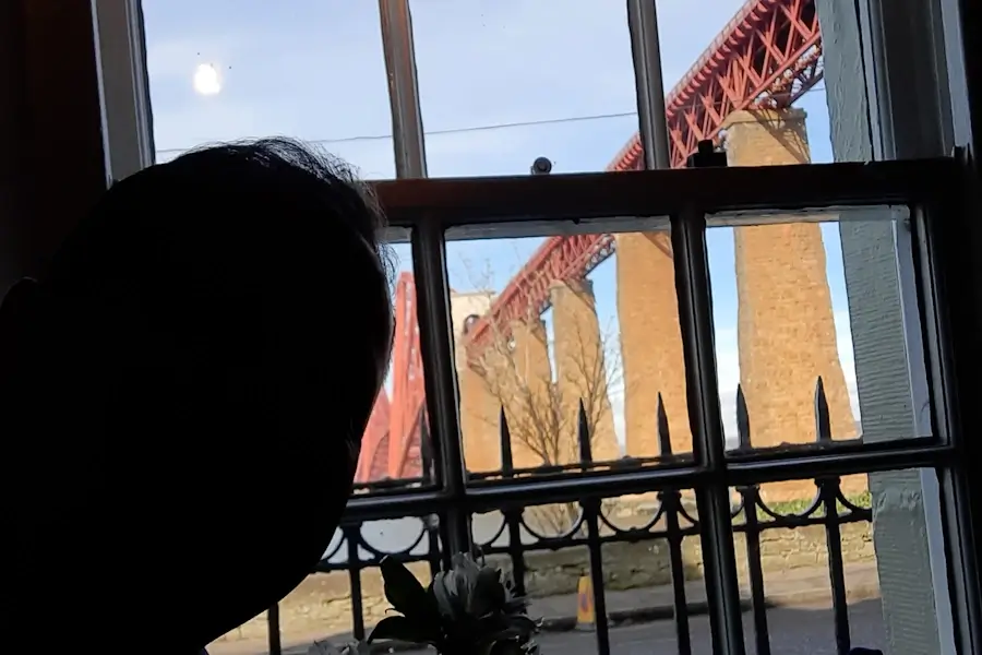 View of the Forth Bridge from inside the Hawes Inn, seen through a traditional window with railings - one of the most popular choices of where to eat in south queensferry