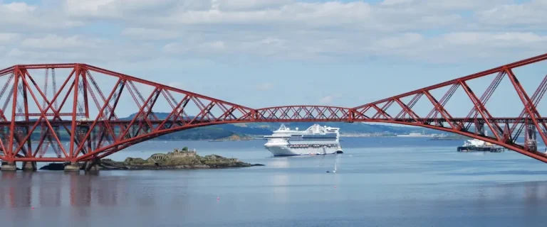 Scotland cruise guide hero image showing a cruise ship sailing under the Forth Bridge at South Queensferry