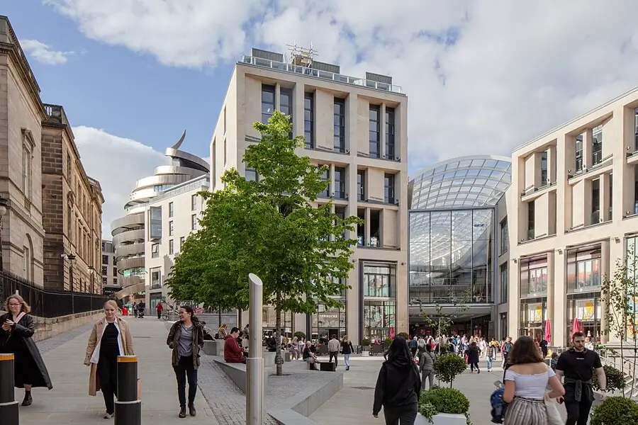 St James Quarter shopping and dining complex at the east end of New Town and Princes Street, Edinburgh, with modern buildings, glass roof, and pedestrians walking through the plaza.