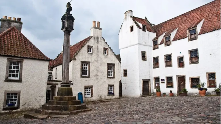 Mercat Cross in Culross village square, filming location for Cranesmuir in Outlander, with whitewashed 17th-century buildings and red pantile roofs
