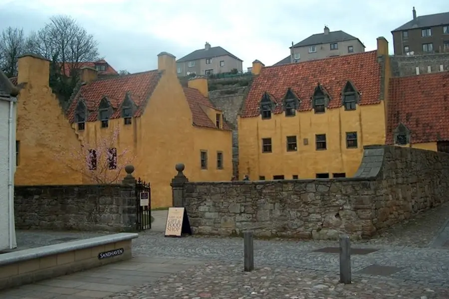 Ochre-coloured Culross Palace buildings with red pantile roofs and stone courtyard wall, filming location for Cranesmuir in Outlander