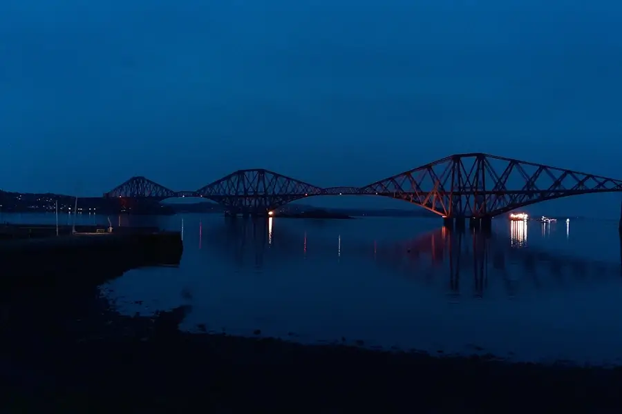 forth bridge at night time with cruise ship in anchored in the firth of forth in the background